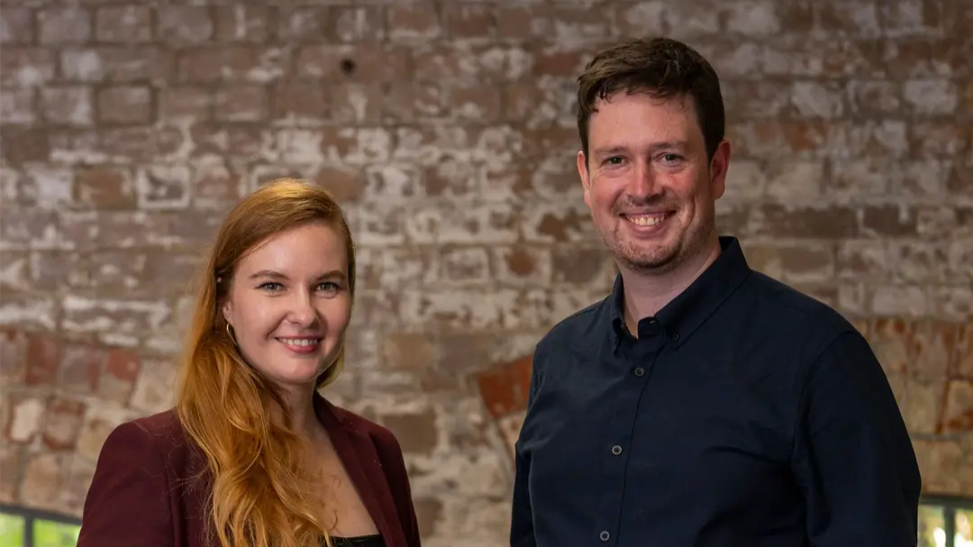 Syenta co-founders Dr Jekaterina Viktorova (Chief Executive Officer) and Ben Wilkinson (Chief Technology Officer). standing together in front of a brick wall. 