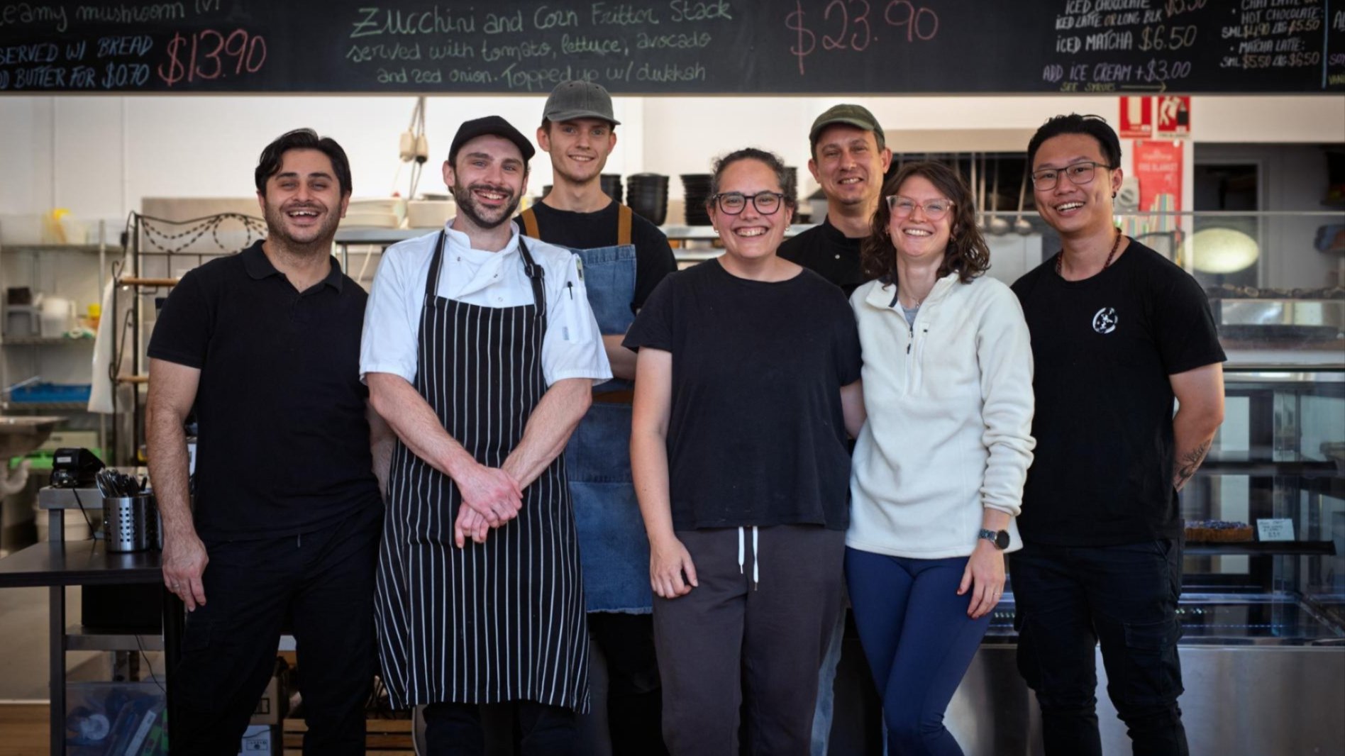 Staff members from Savoir French caf&eacute; standing together and smiling inside the caf&eacute; at the ANU School of Art and Design.