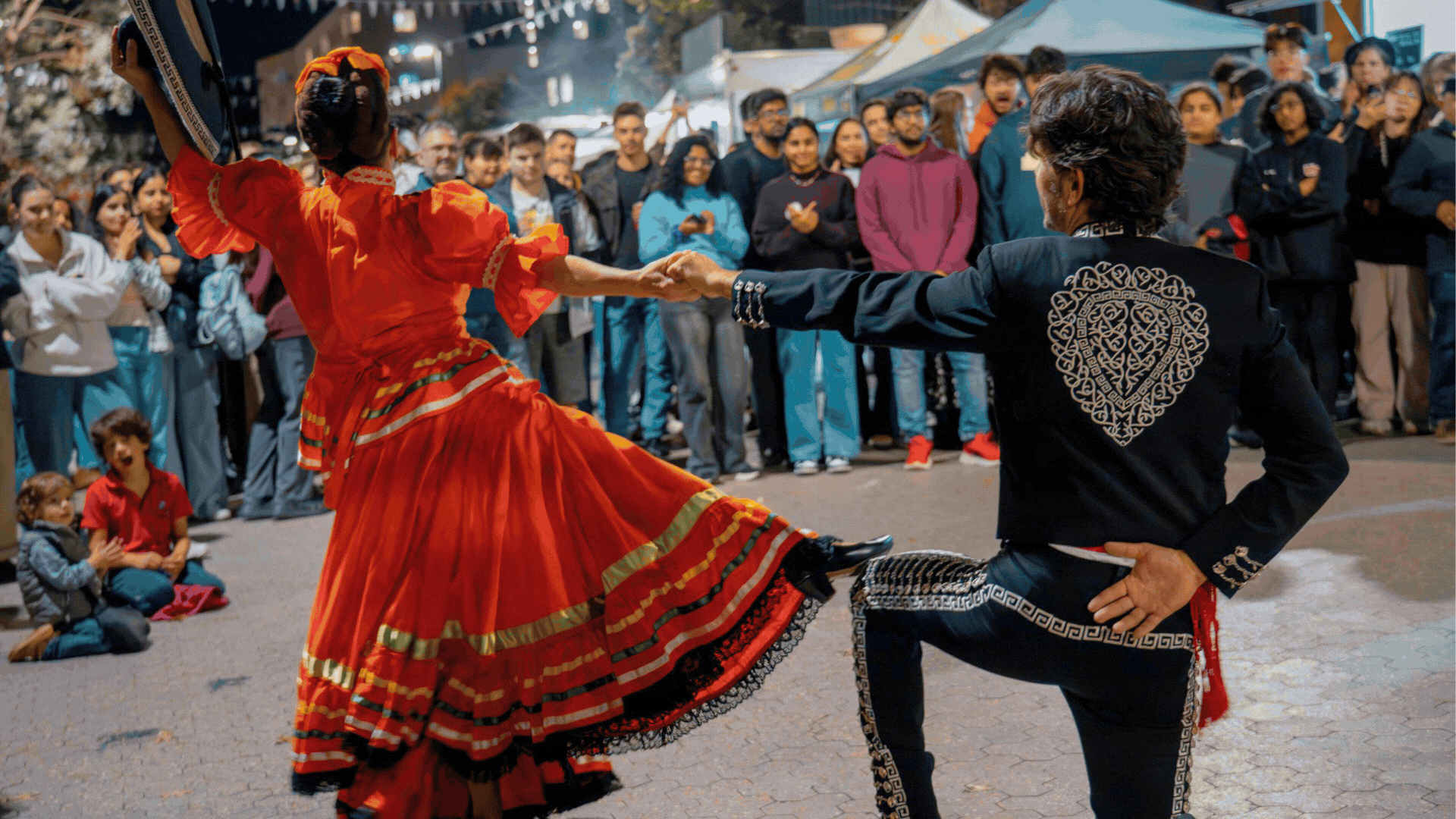 Scenes from the ��������Latin American Night Markets on Uni Avenue, featuring traditional dancers in costume, couples dancing in the crowd and students gathering at food stalls under string lights.