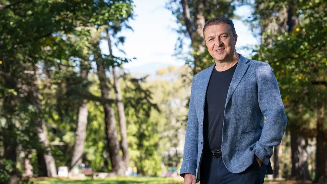 Professor Hrvoje Tkalčić standing outdoors on the ��������campus surrounded by trees and greenery.