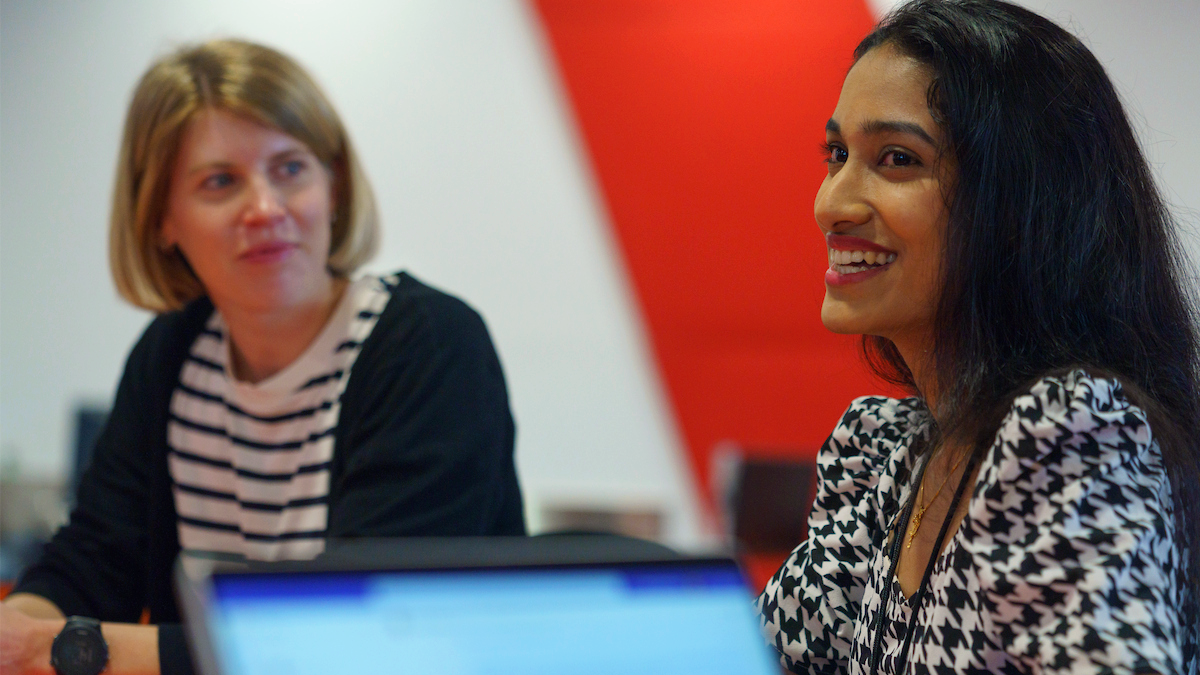ANU Staff members seated in a at a desk during a workshop, smiling and taking notes during a professional development session.