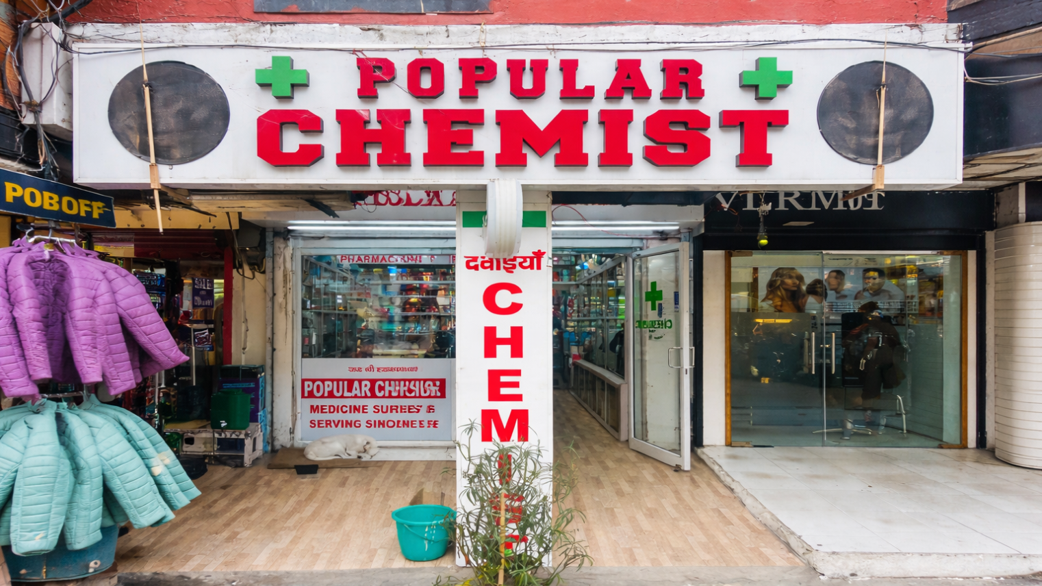 Storefront of a pharmacy with large &ldquo;POPULAR CHEMIST&rdquo; signage and open entrance displaying medicines inside.