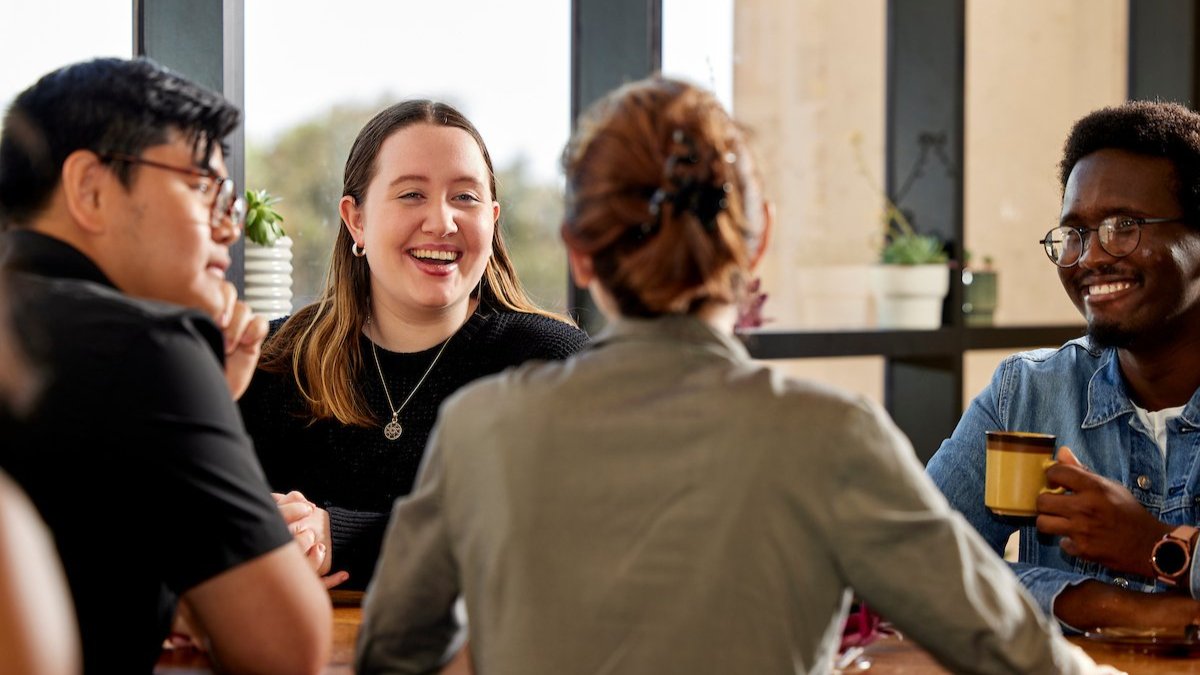 Adults seated in a at a desk during a workshop, smiling and taking notes during a professional development session.