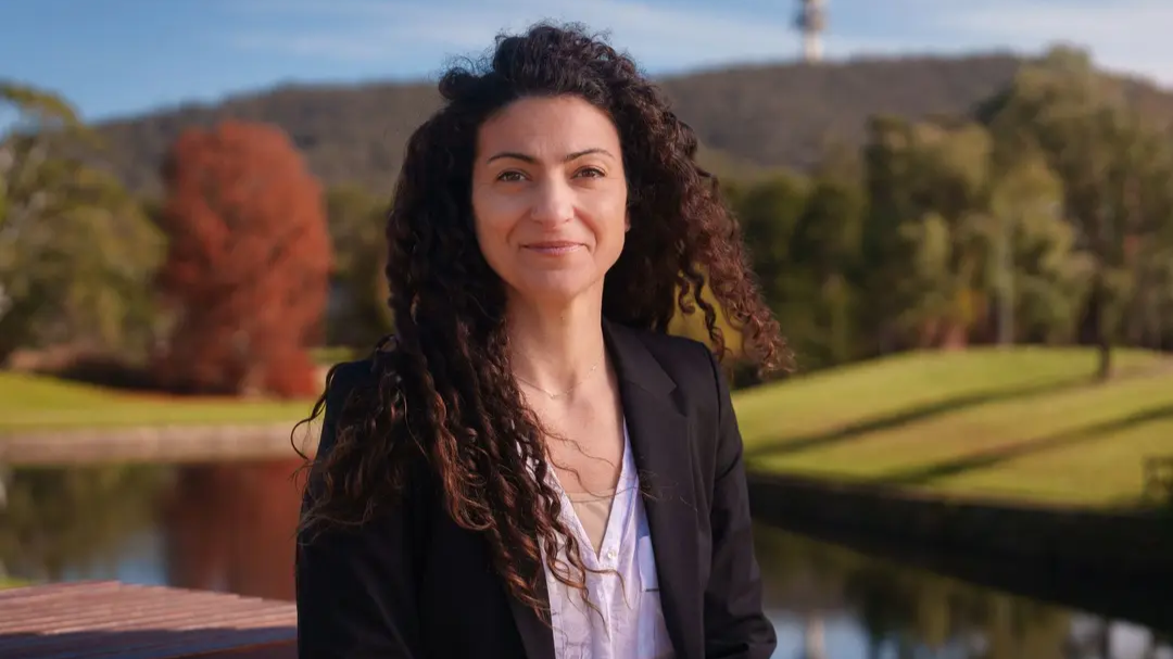 Associate Professor Ana Sequeira in a blazer in front of Sullivan's Creek at ANU. 