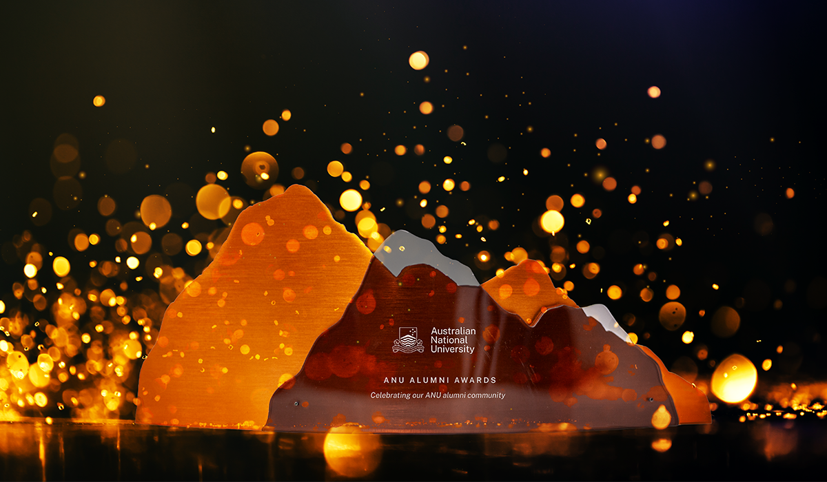 ANU Alumni Awards trophy shaped like mountains, lit by warm golden lights on a dark background. 