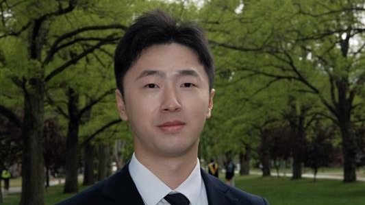 CPortrait of Bruce Pan in a black blazer and tie in a garden