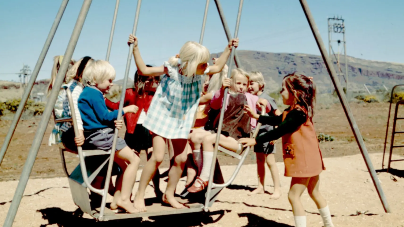 Multiple children playing on a swing together 