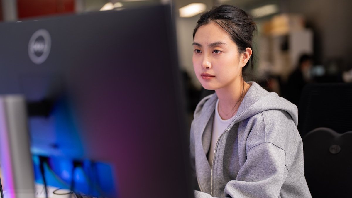 Woman working at a computer in an office, focused on the screen.