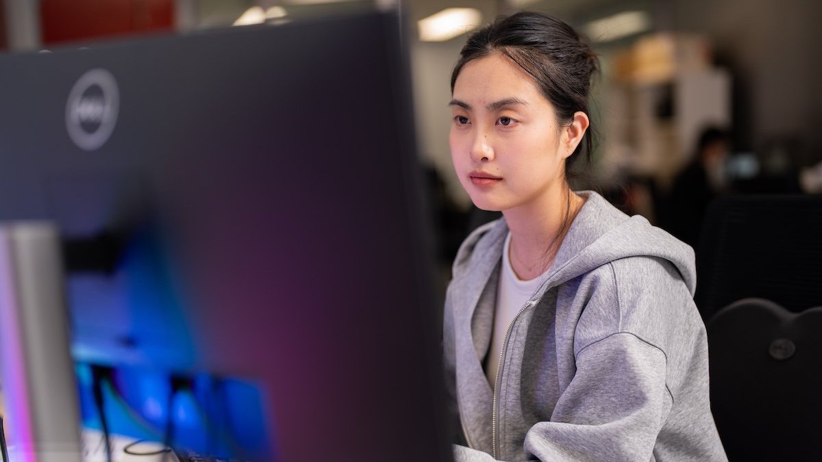Woman working at a computer in an office, focused on the screen.