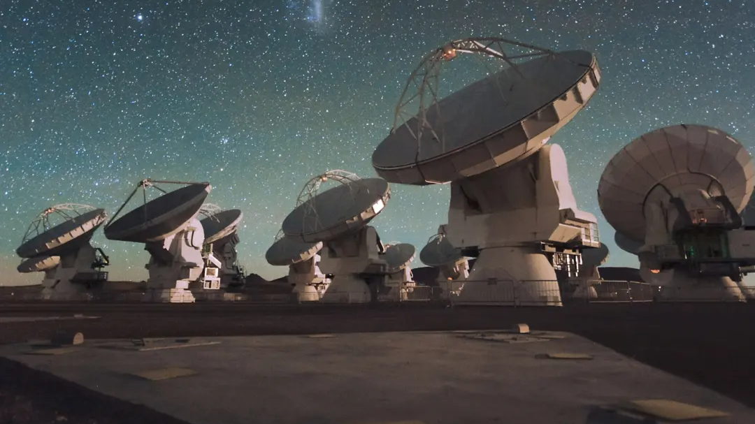 Multiple antennas of the ALMA telescope under a starry night sky. 