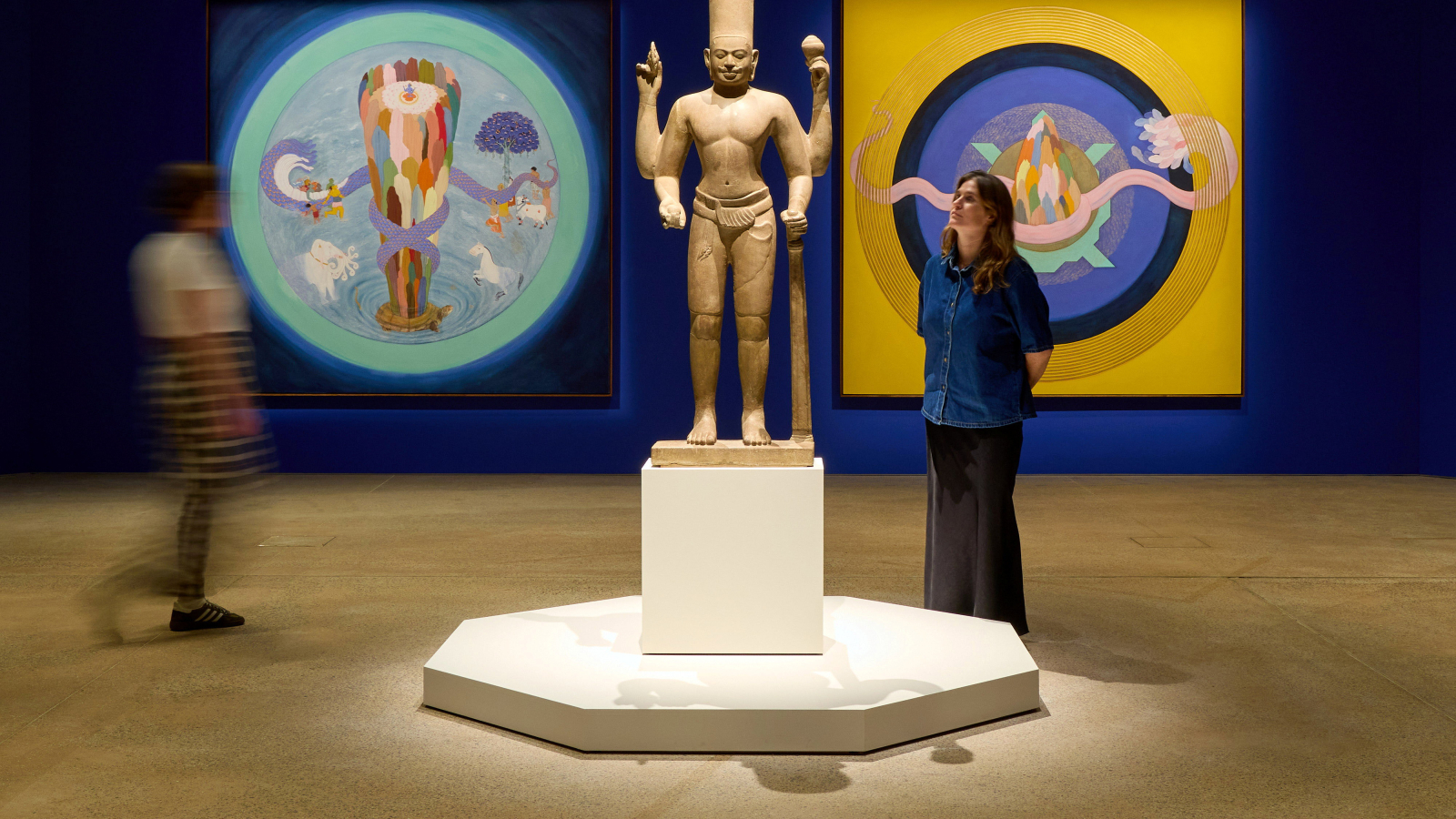 Woman standing beside a sculpture in an art gallery.