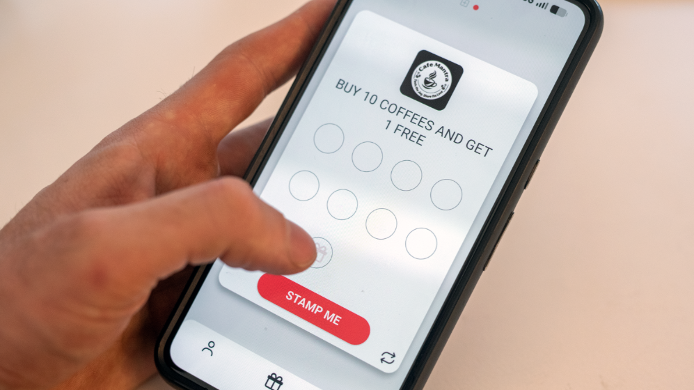 Hand using the Stamp Me rewards app on a smartphone screen.