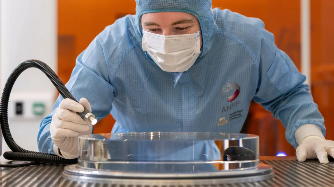 Technical officer manoeuvring glass substrate prior to polishing in the ANU Research School of Physics cleanroom. 