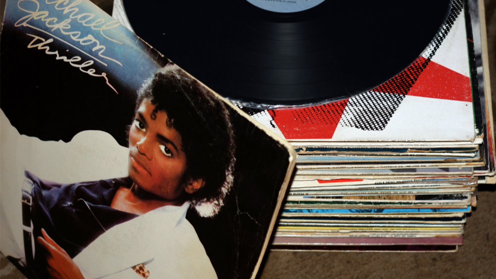 Michael Jackson&rsquo;s Thriller album cover leans against a stack of records, with a black vinyl record resting on top.