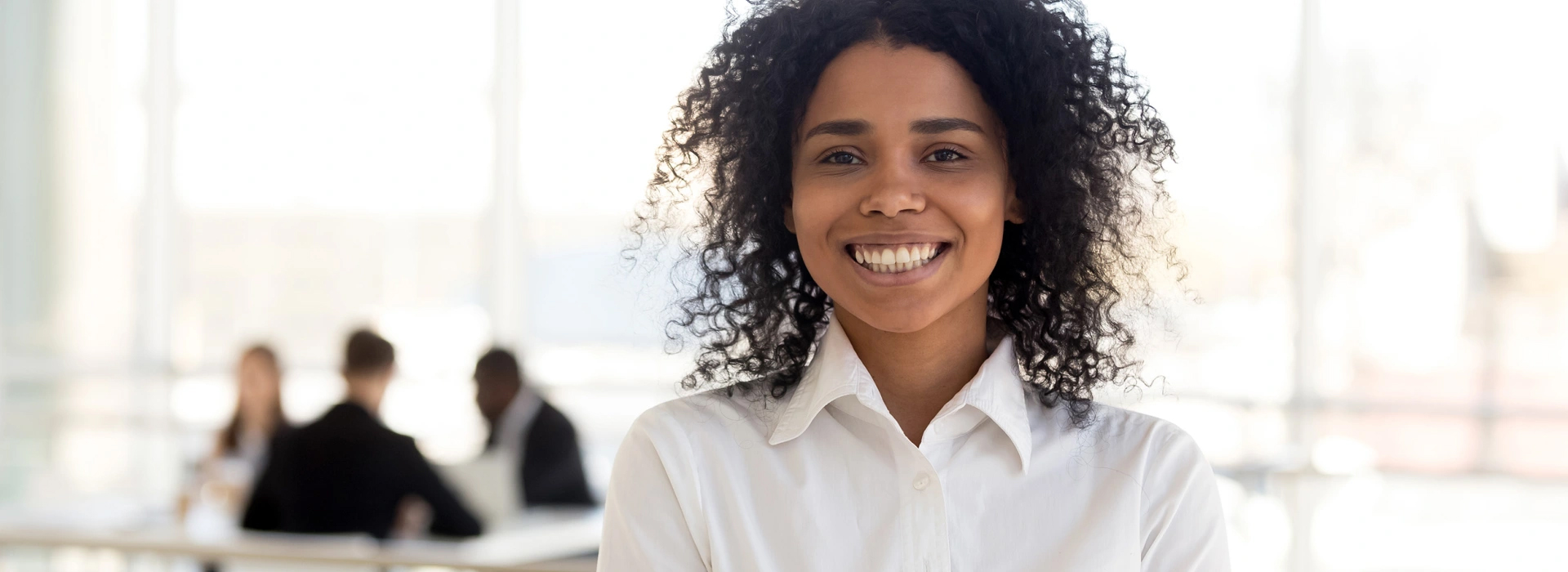 Smiling woman in a white shirt in a bright office.