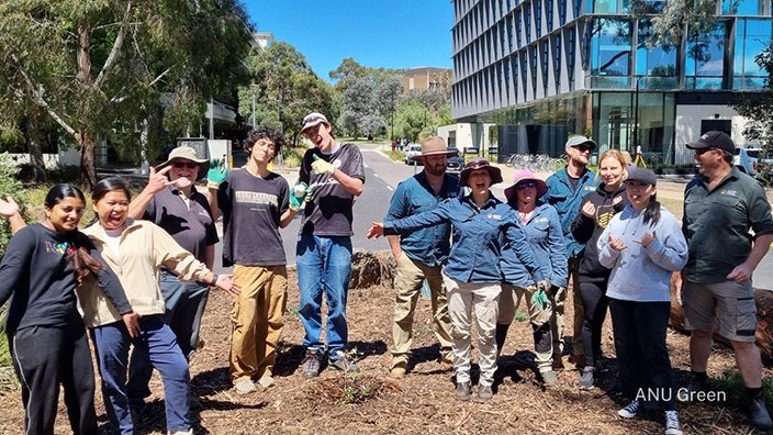 Group of volunteers standing in a freshly mulched garden bed on the ANU campus after a community gardening activity.