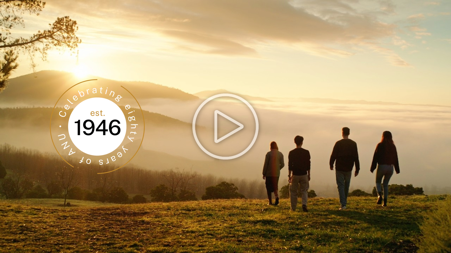 Four people walk toward a scenic mountain sunrise with a 