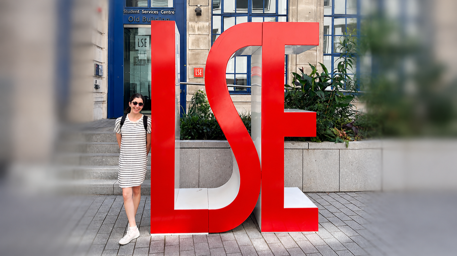 HDR student Sharon Rosenrauch standing next to the London School of Economics logo